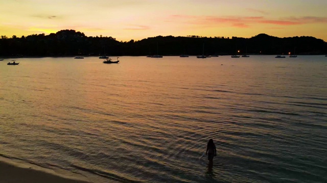 时光流逝拍摄日落时海浪拍打沙滩的海景，渔船停泊在沙滩上视频下载