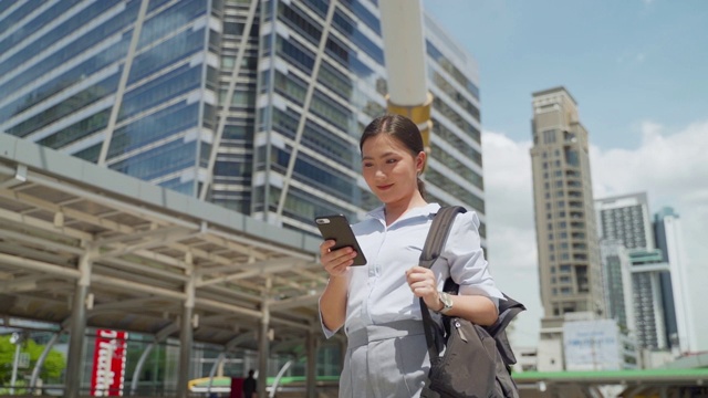 亚洲人用智能手机在城市里慢动作走路和说话视频素材