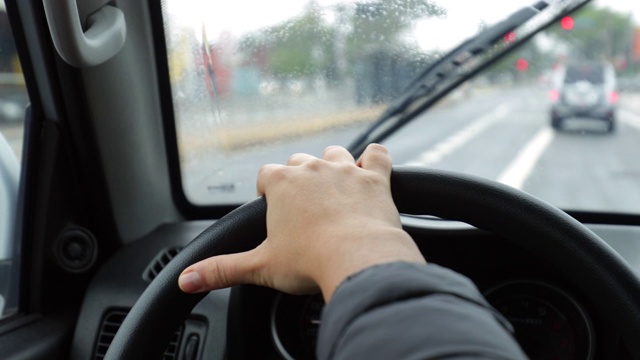 女性手握方向盘行驶在道路上的特写视频素材