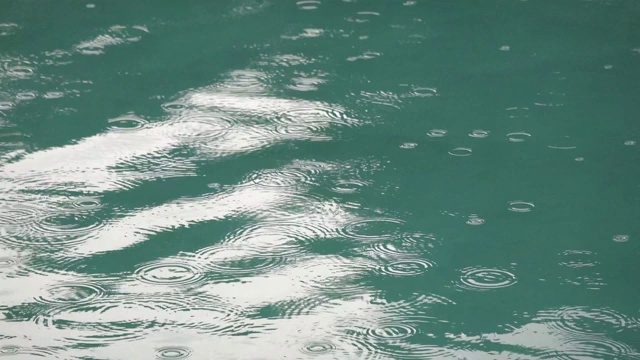 热带夏雨溅进游泳池。在暴风雨和雨滴落进水里游泳池的特写。视频素材