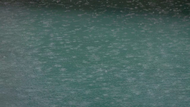 热带夏雨溅进游泳池。在暴风雨和雨滴落进水里游泳池的特写。视频素材