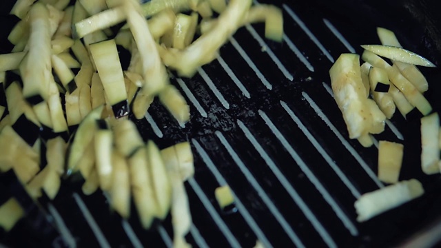 茄子片在煎锅里用油煎，厨师用铲子把它们混合在一起视频素材