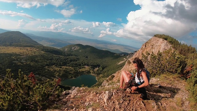 一个女人带着她的宠物狗在山里徒步旅行视频素材