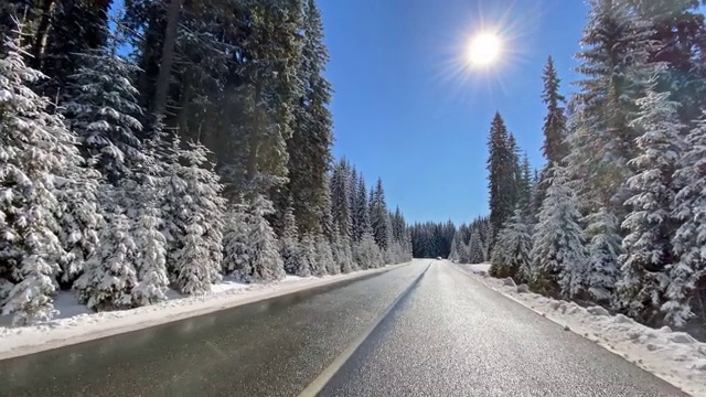 冬天，在白雪覆盖的森林里，行驶在空旷的道路上视频素材