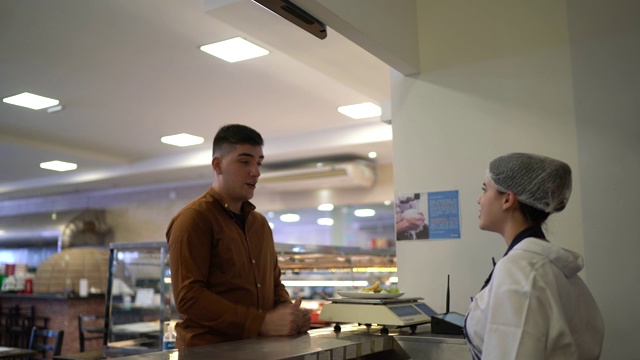 顾客在自助餐厅给他的饭菜称重视频素材