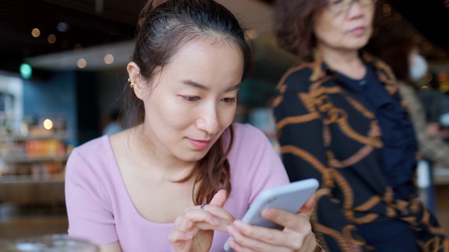 一个年轻的亚洲女人在咖啡店打电话视频素材