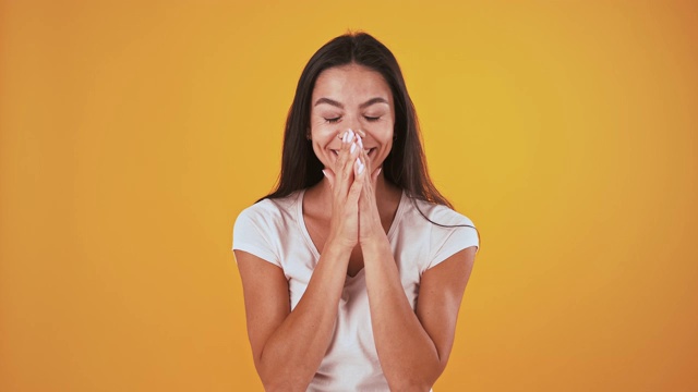 惊讶和狂喜的女人说哇，微笑着，在橙色的背景下摆姿势视频素材