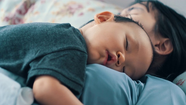 小男孩在卧室里睡在妈妈的胸口上视频素材