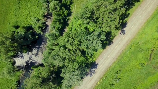 空中飞行:飞过公路和森林。太阳眩光是可见的。看来,垂直下降。视频素材