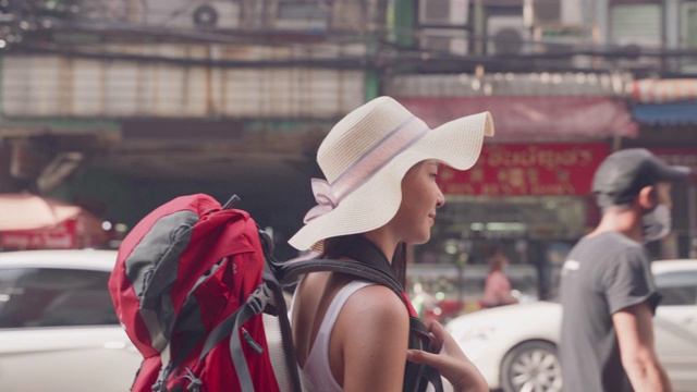 中国妇女，20-30岁，戴着帽子和背包，走在姚瓦拉特路。泰国著名的街头小吃视频素材