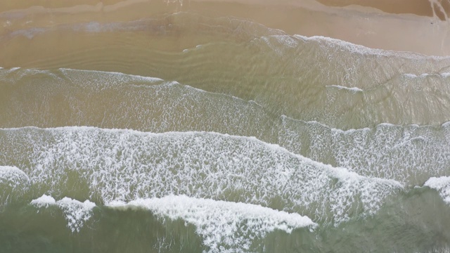 海面或海浪的鸟瞰图。泡沫状的海浪翻滚着涌向沙滩。莱姆美芬海滩视频素材