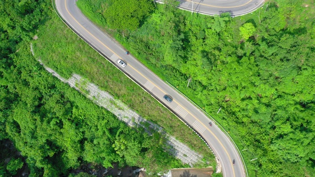 泰国绿树成荫的森林之间美丽的公路鸟瞰图。汽车在路上行驶。视频素材