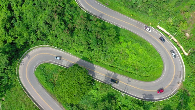 泰国绿树成荫的森林之间美丽的公路鸟瞰图。汽车在路上行驶。视频下载