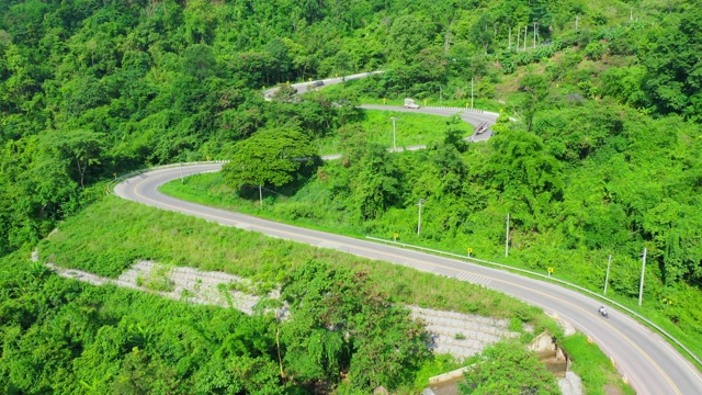 泰国绿树成荫的森林之间美丽的公路鸟瞰图。汽车在路上行驶。视频下载