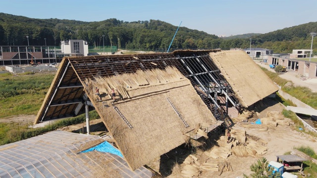 鸟瞰图一个大房子的屋顶与干稻草和干草。安装屋顶的工人。视频素材