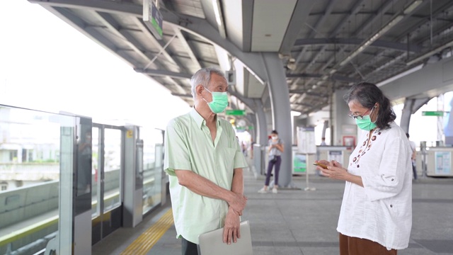 亚洲老年夫妇戴着防护口罩排队等火车视频素材