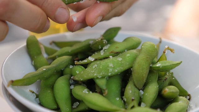 用手把毛豆从豆荚里挤出来。时尚的素食日本街头小吃视频素材