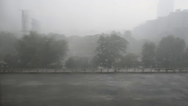 恶劣的天气雨天高角度的视野，停车场屋顶，淹没了树木和办公楼的背景视频素材