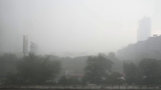 恶劣的天气雨天高角度的视野，停车场屋顶，淹没了树木和办公楼的背景视频素材