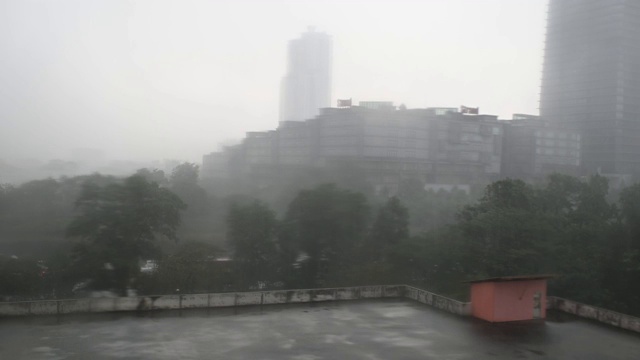 恶劣的天气雨天高角度的视野，停车场屋顶，淹没了树木和办公楼的背景视频素材