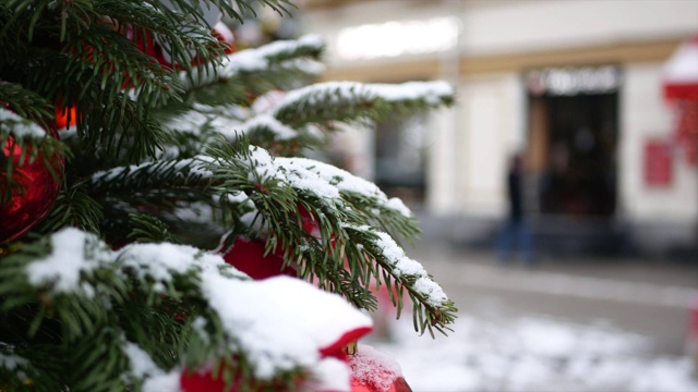 云杉树枝上的雪和圣诞玩具在前景和冬天的街道在背景视频素材