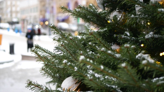 云杉树枝上的雪和圣诞玩具在前景和冬天的街道在背景视频素材