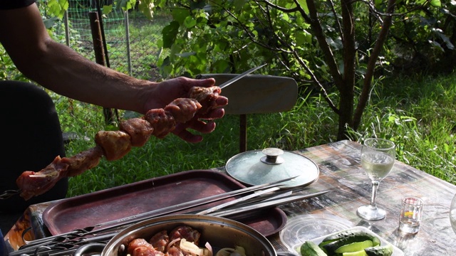 男性的手拿起生肉串，放在金属串上视频素材