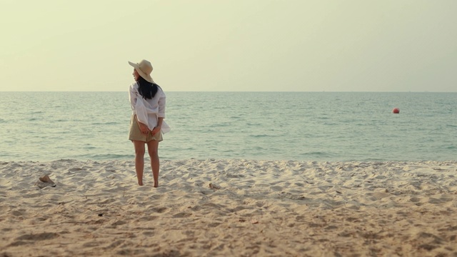 快乐的亚洲女人跑到海滩上举起手臂庆祝旅游假期夏天惊人的美丽的海洋和沙滩的景色日落。视频素材