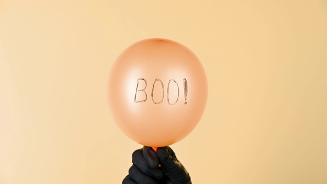 黄色背景上的“Boo”字样的橙色气球膨胀起来。视频素材