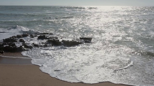 风平浪静的下午，沙滩上的波浪起伏视频素材