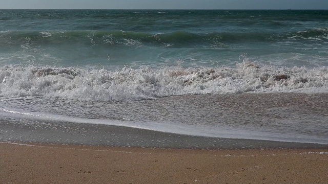 风平浪静的下午，沙滩上的波浪起伏视频素材