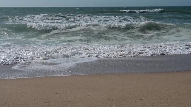 风平浪静的下午，沙滩上的波浪起伏视频素材