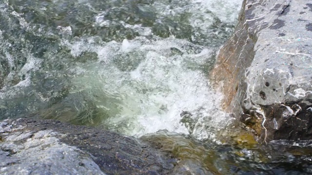 泉水河水在两大块岩石之间流动，特写细节，慢动作视频视频素材