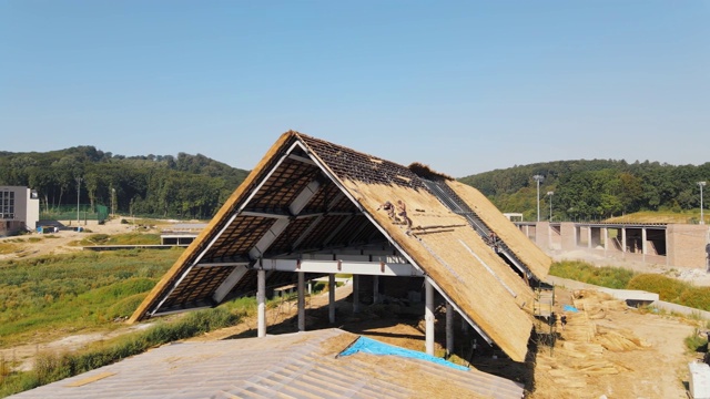 鸟瞰图一个大房子的屋顶与干稻草和干草。安装屋顶的工人。视频素材