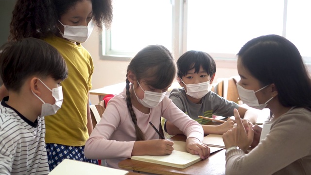 一群不同的学生在教学楼讨论小组学习课。小学生们在头脑风暴时戴着口罩。视频素材