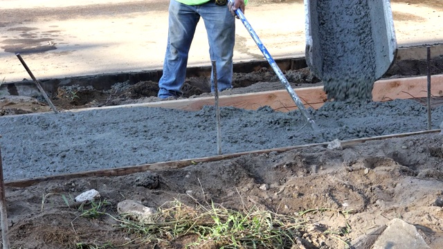 劳工建筑工在建筑工地用水泥工人在模板上浇筑新的人行道混凝土视频素材