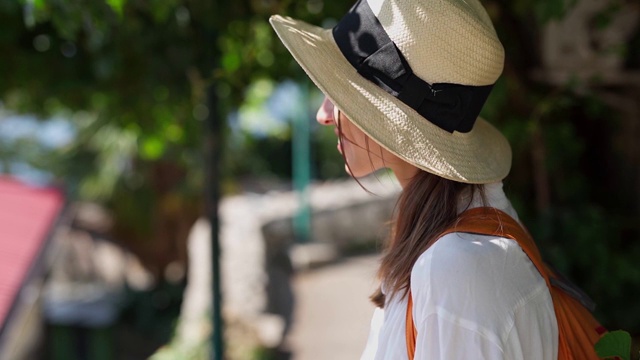 一脸自信快乐的女子旅行者戴着草帽站在绿城街道上视频素材