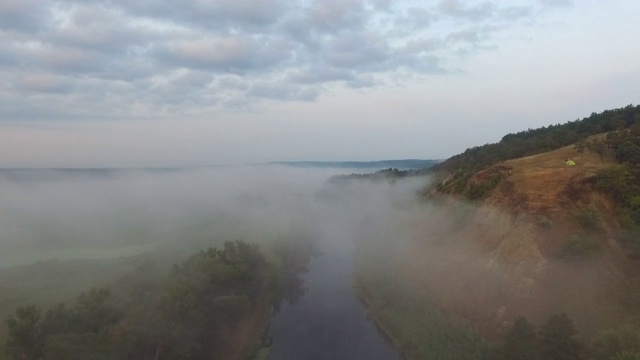 航拍清晨美丽的乡村环境。令人惊叹的风景朦胧的山谷和河流在黎明。在有雾的广阔草地上空飞翔。平静的自然场景。慢动作视频素材