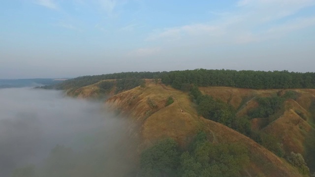 航拍清晨美丽的自然景观。山顶和山谷被浓雾覆盖，景色令人惊叹。飞行在美好的乡村环境。慢动作视频素材