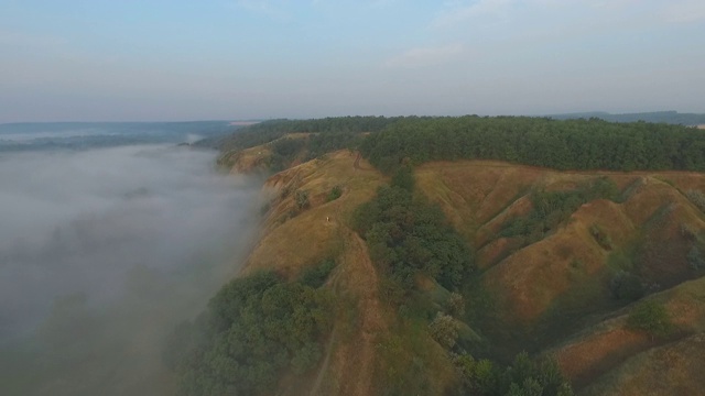 航拍清晨美丽的自然景观。山顶和山谷被浓雾覆盖，景色令人惊叹。飞行在美好的乡村环境。慢动作视频素材