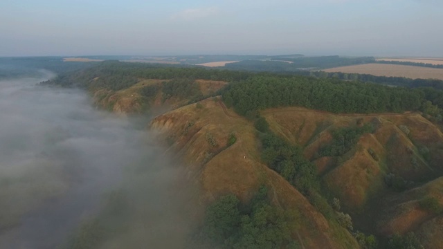 航拍清晨美丽的自然景观。山顶和山谷被浓雾覆盖，景色令人惊叹。飞行在美好的乡村环境。慢动作视频素材