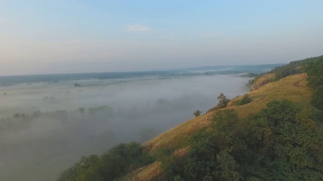 航拍清晨美丽的自然景观。山顶和山谷被浓雾覆盖，景色令人惊叹。飞行在美好的乡村环境。慢动作视频素材