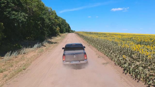 空中拍摄的黑色皮卡快速驶过空旷的乡村公路。越野车辆在尘土飞扬的道路上行驶。在夏天的乡村路上开车飞过。农业的概念。视频素材