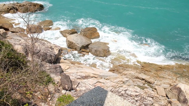 汹涌的海浪和水花拍打在带有海水泡沫的岩石海滩上。湛蓝的海水，海边，石头海岸视频素材