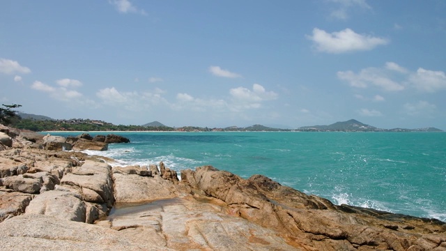 汹涌的海浪和水花拍打在带有海水泡沫的岩石海滩上。湛蓝的海水，海边，石头海岸视频素材