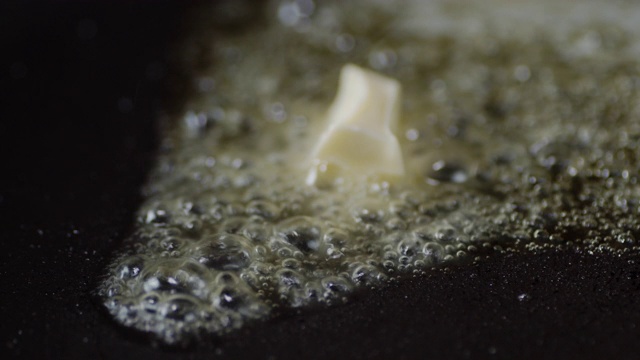 一片黄油在带有气泡的煎锅中沸腾。视频素材