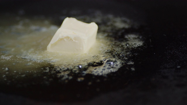 一块带气泡的黄油在锅里融化。视频素材