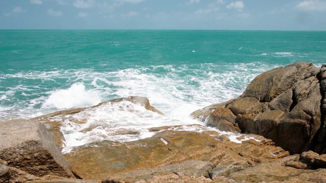 汹涌的海浪和水花拍打在带有海水泡沫的岩石海滩上。湛蓝的海水，海边，石头海岸视频素材