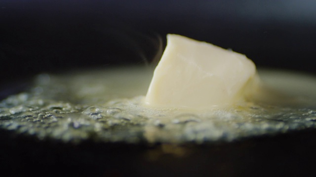 在煎锅里，一块黄油在热蒸汽中融化。视频素材