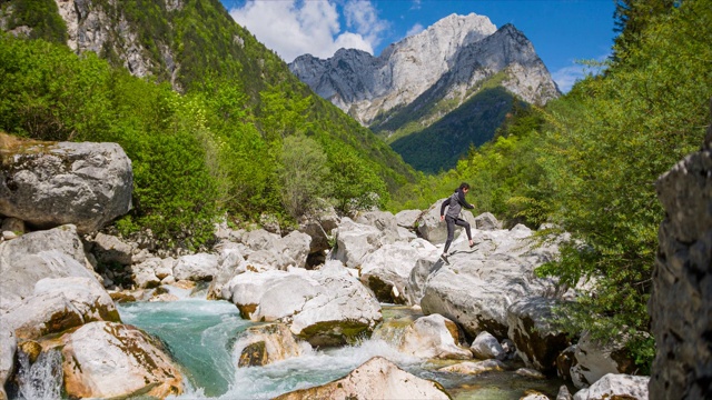 年轻人翻山越岭，从一块石头跳到另一块石头视频素材